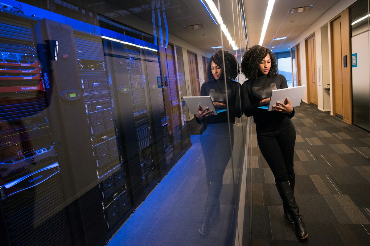 IT specialist holding a laptop beside a glass server room